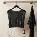 A black sequined cropped top and matching draped scarf hanging from a brass rod on a beige wall, with a small shelf and neutral decor below.